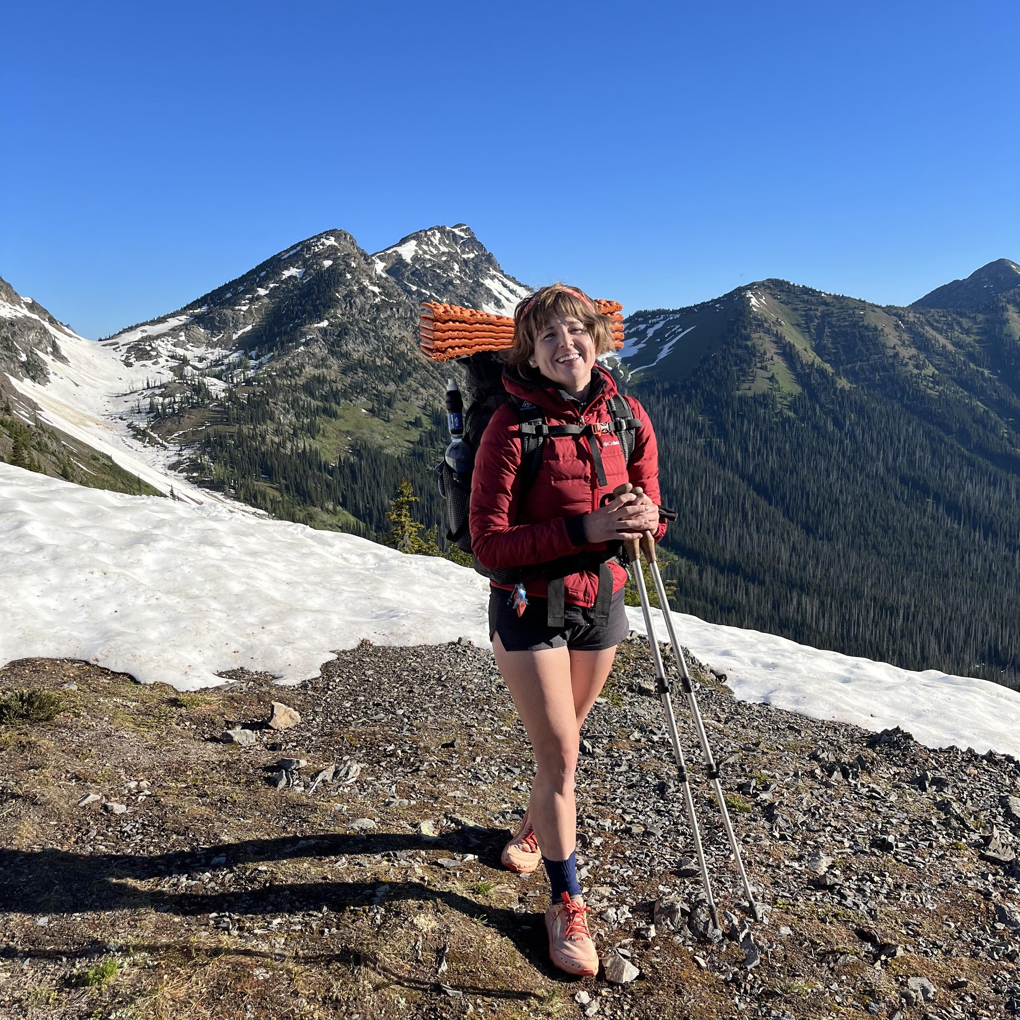 Jen Holton on a mountain trail with a backpack and trekking poles